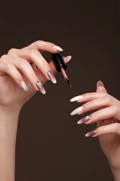 Hermosa manicura clásica en mano femenina con aceite para cutículas. Primer plano . — Foto de Stock