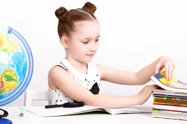 Menina engraçada na mesa de um aluno do primeiro ano . — Fotografia de Stock