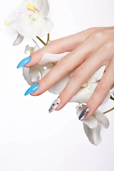 Beautiful summer blue manicure on female hand with flowers . Close-up. — Stock Photo, Image