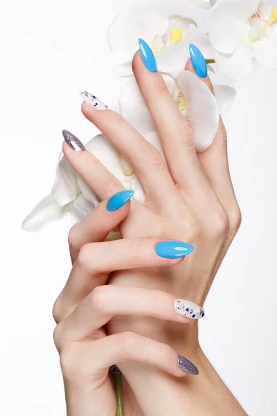 Beautiful summer blue manicure on female hand with flowers . Close-up. — Stock Photo, Image