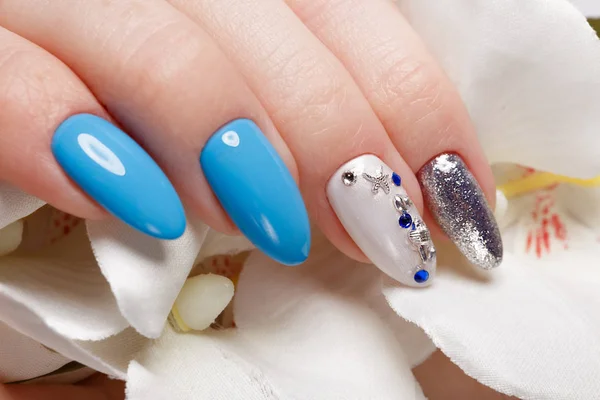 Beautiful summer blue manicure on female hand with flowers . Close-up. — Stock Photo, Image