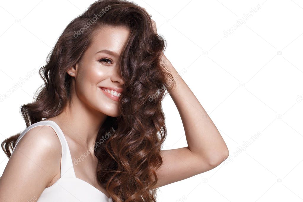 Beautiful young girl in white dress with natural make-up, hair curls and smile. Beauty face. Photo taken in the studio.