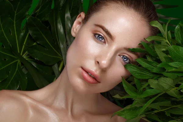 Hermosa chica fresca con la piel perfecta, maquillaje natural y hojas verdes. Cara de belleza . —  Fotos de Stock