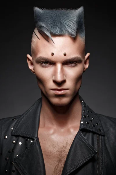 Young man with blue hair and creative makeup and hair.