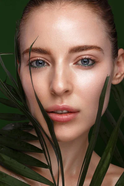 Hermosa chica fresca con crema cosmética en la cara, maquillaje natural y hojas verdes. Cara de belleza . —  Fotos de Stock