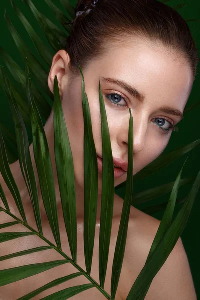 Belle fille fraîche avec crème cosmétique sur le visage, maquillage naturel et feuilles vertes. Beauté visage . — Photo