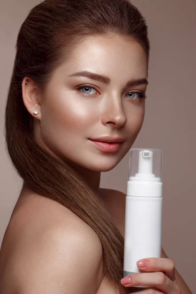 Hermosa joven con maquillaje natural desnudo con cosméticos en las manos. Cara de belleza . — Foto de Stock