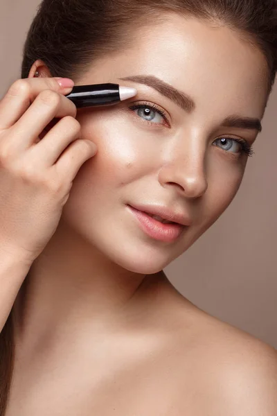 Mooi jong meisje met natuurlijke naakt make-up- en markeerstiftinstellingen potlood. Schoonheid gezicht. — Stockfoto