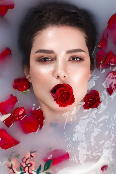 Beautiful girl with classic make-up and red lips in the bathroom with flowers. Beauty face.