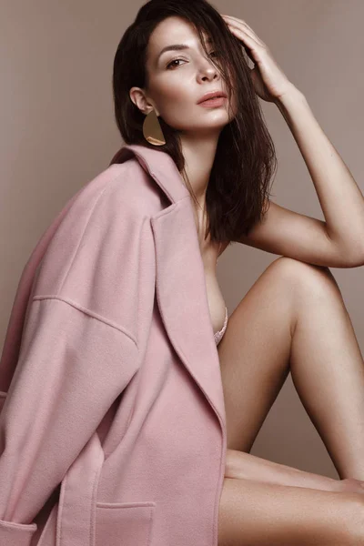 Una bella ragazza con il trucco classico e un'acconciatura in un cappotto di design alla moda in posa in uno studio. Bellezza viso . — Foto Stock