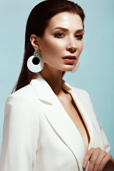 Vacker flicka med klassiska make-up och hår-stil i en trendig designer vit jacka poserar i en studio. Vackert ansikte. — Stockfoto