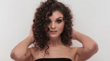 Güzel esmer kız mükemmel kıvırcık saçlı ve klasik makyaj stüdyoda poz. Güzellik.