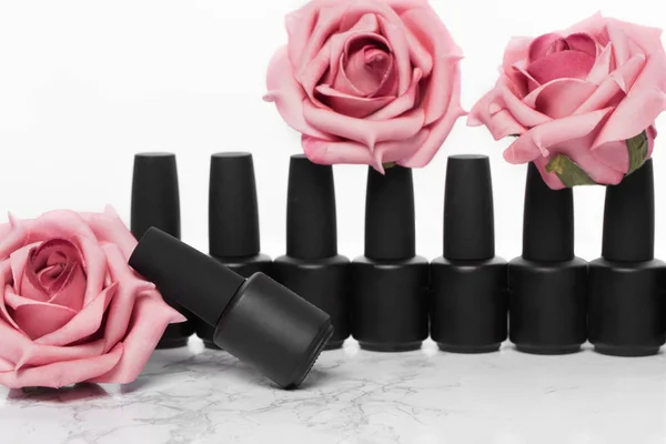 Bottiglie nere di smalto su uno sfondo di fiori. Design della manicure . — Foto Stock