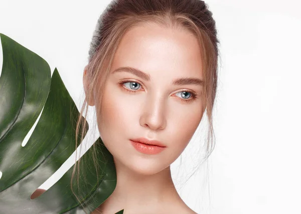 Piękna słodka dziewczyna z idealną skórą, naturalnym makijażu i zielonymi liśćmi. Piękna twarz. — Zdjęcie stockowe