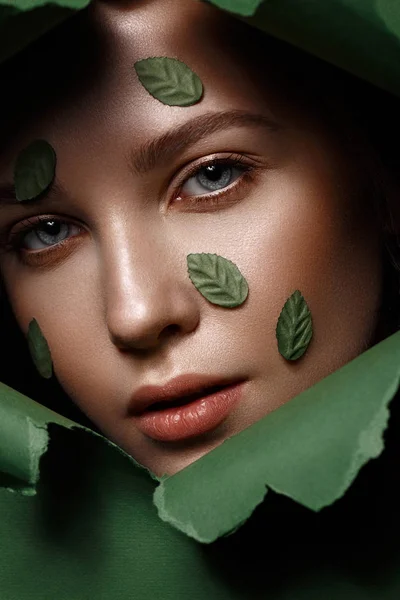 Belle fille fraîche avec une peau parfaite, maquillage naturel et feuilles vertes. Un beau visage. Gros plan — Photo