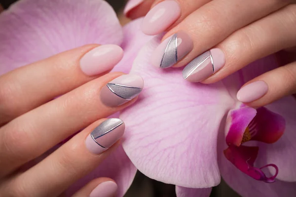 Purple neat manicure on female hands on flowers background. Nail design — Stock Photo, Image