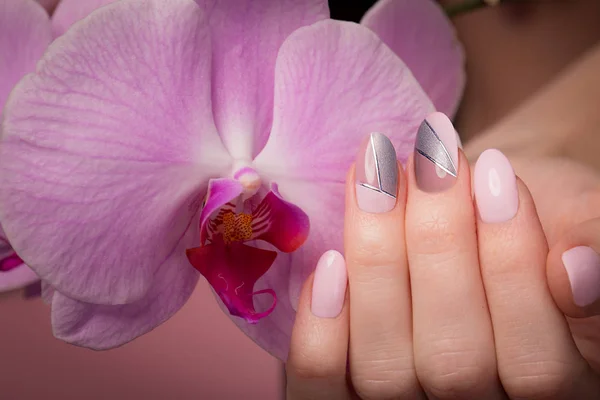 Manicure ordinata viola su mani femminili su sfondo di fiori. Progettazione unghie — Foto Stock