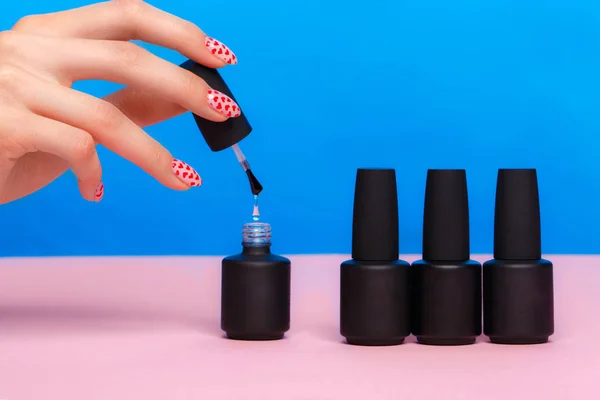 Botellas negras de esmalte de uñas sobre un fondo colorido. Diseño de manicura — Foto de Stock