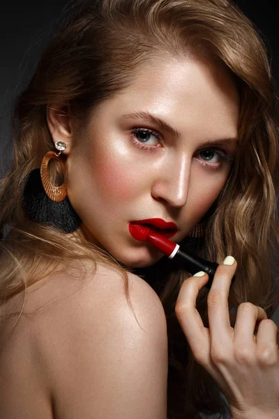 Menina bonita com lábios vermelhos e maquiagem clássica e cachos com batom na mão. Cara de beleza . — Fotografia de Stock