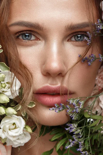 Schöne Frau mit klassischem Nude Make-up, leichter Frisur und Blumen. Schönheit Gesicht. — Stockfoto