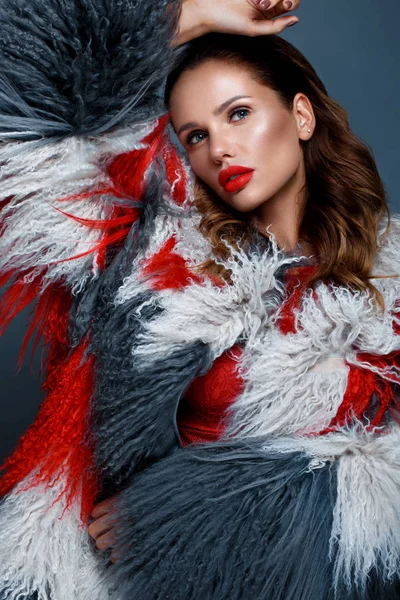 Beautiful woman with classic holiday make-up, red lips, curls in a multi-colored llama coat. Beauty face. — Stock Photo, Image