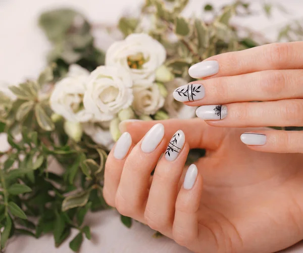 Delikatny schludny manicure na kobiecych rękach na tle kwiatów. Projektowanie paznokci — Zdjęcie stockowe