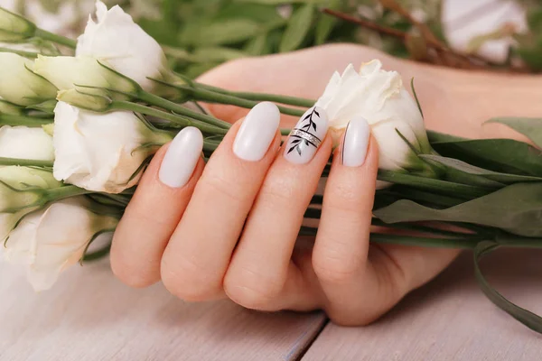 Delikatny schludny manicure na kobiecych rękach na tle kwiatów. Projektowanie paznokci — Zdjęcie stockowe