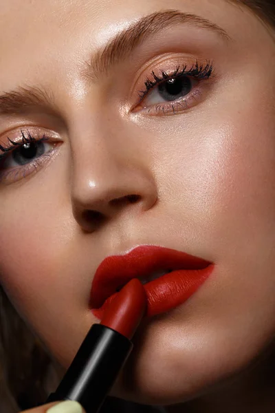 Hermosa chica con labios rojos y maquillaje clásico con lápiz labial en la mano. Cara de belleza — Foto de Stock