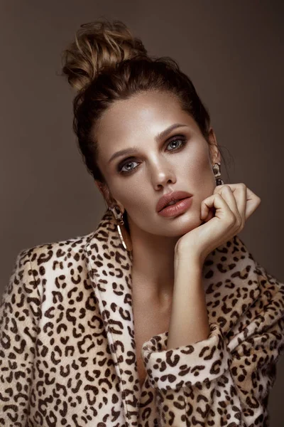Piękna seksowna Kobieta w płaszcz i kolczyki Leopard, z klasycznym Smokey makijażu i modnej fryzury. Piękna twarz. — Zdjęcie stockowe