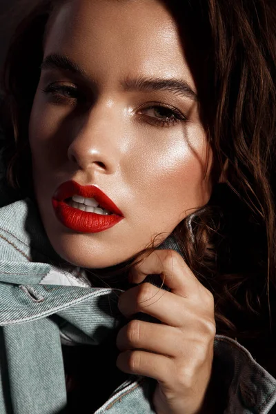 Hermosa chica sexy con maquillaje brillante, labios rojos, cabello mojado en una chaqueta de mezclilla. Cara de belleza. — Foto de Stock