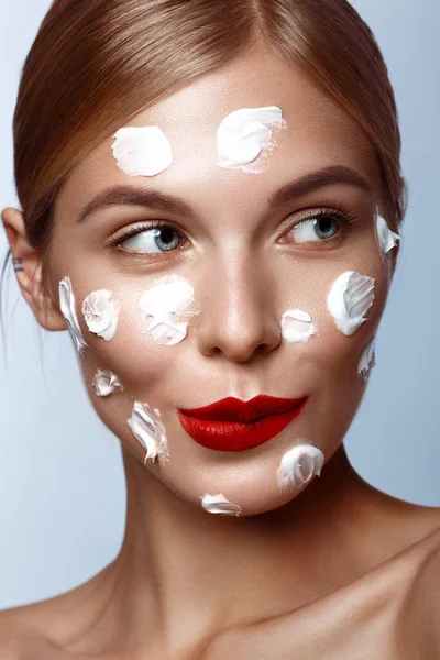 Vacker fräsch tjej med kosmetisk kräm i ansiktet, naturlig make-up och röda läppar. Skönhetsansikte. — Stockfoto