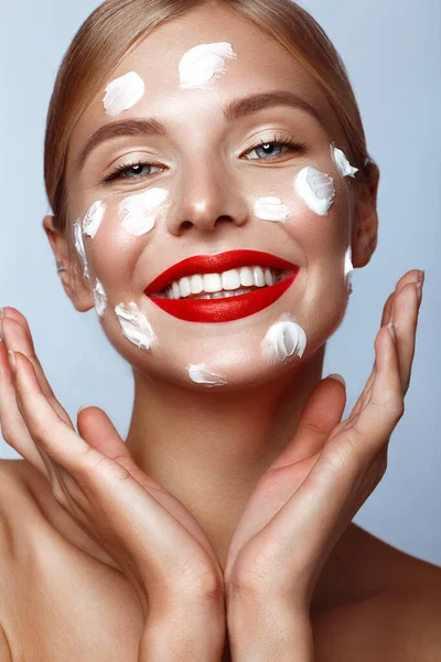 Beautiful fresh girl with cosmetic cream on the face, natural make-up and red lips. Beauty face. — Stock Photo, Image