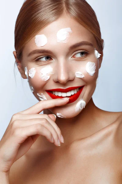 Vacker fräsch tjej med kosmetisk kräm i ansiktet, naturlig make-up och röda läppar. Skönhetsansikte. — Stockfoto