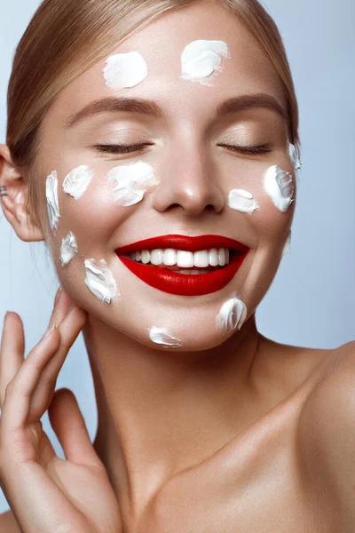 Beautiful fresh girl with cosmetic cream on the face, natural make-up and red lips. Beauty face. — Stock Photo, Image
