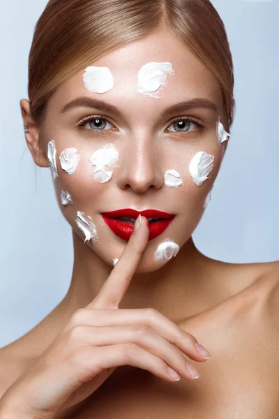 Beautiful fresh girl with cosmetic cream on the face, natural make-up and red lips. Beauty face. — Stock Photo, Image