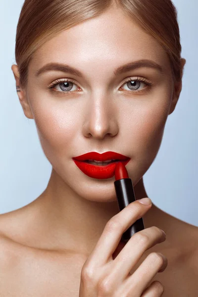 Piękna dziewczyna z czerwonymi ustami i klasycznym makijażem z szminką w ręku. Piękna twarz — Zdjęcie stockowe