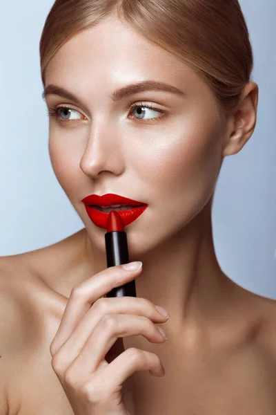 Belle fille aux lèvres rouges et au maquillage classique avec du rouge à lèvres à la main. Beauté visage — Photo