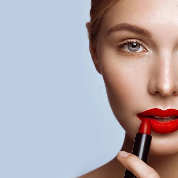 Красивая девушка с красными губами и классический макияж с помадой в руке. Красота лица — стоковое фото