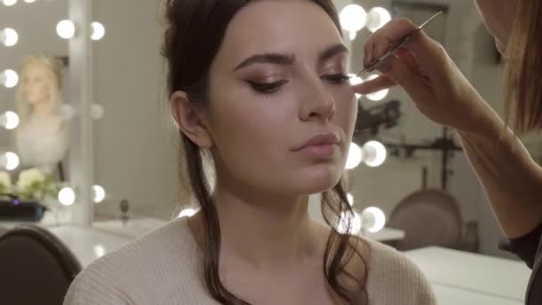 Make-up kunstenaar lijmt wimpers modellen in een make-up salon. Schoonheidsgezicht. — Stockvideo
