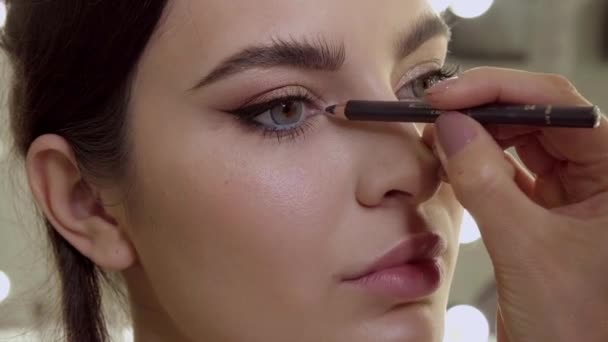 Makijaż artysta maluje modele oczu w kosmetycznym salonie makijażu. Piękna twarz. — Wideo stockowe