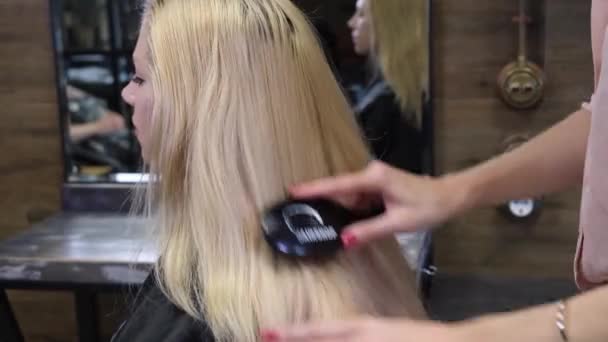 Förberedelse av hårmodell för färgning. Frisören kammar det blonda håret innan frisyren klipps. Skönhetssalong, frisör. — Stockvideo