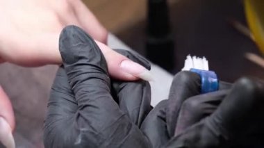 Usta, manikürcüdeki müşteriye hijyenik manikür yapıyor. Kesici kullanılarak kesme işlemi.