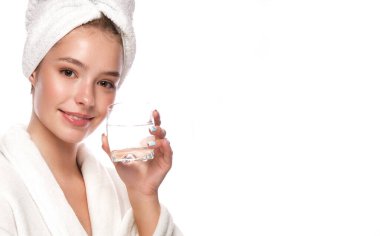 Temiz tenli beyaz havluyla genç ve güzel bir kız kameranın önünde ellerinde suyla poz veriyor. Güzel surat. Cilt bakımı.