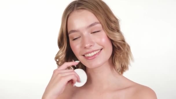 Bella tenera ragazza in un accappatoio bianco casa con la pelle fresca pulita in posa davanti alla fotocamera con una spugna tra le mani. Bellezza. Cura della pelle. — Video Stock