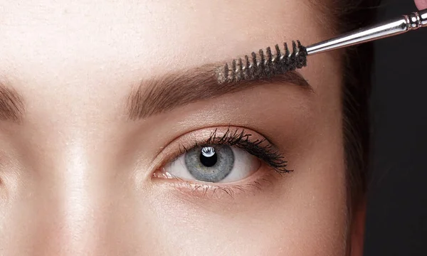 Крупный план женских глаз с щёткой для бровей. Косметика для макияжа глаз. — стоковое фото