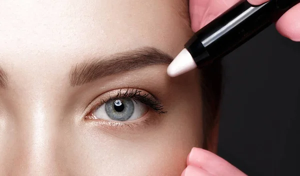 Close-up van vrouwelijke ogen met een wenkbrauwmarkeerstift. Oogmake-up cosmetica. — Stockfoto
