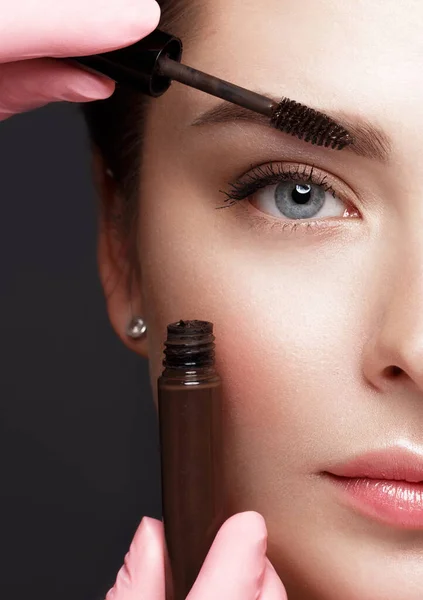 Close-up van vrouwelijke ogen met een wenkbrauwborstel. Oogmake-up cosmetica. — Stockfoto