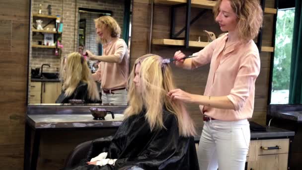 Kuaför, bir güzellik salonunda sarışın müşteri saçı boyuyor. Stüdyo kuaförü — Stok video