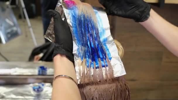 Парикмахер окрашивает светлые волосы клиентов в синий и красный цвет. — стоковое видео