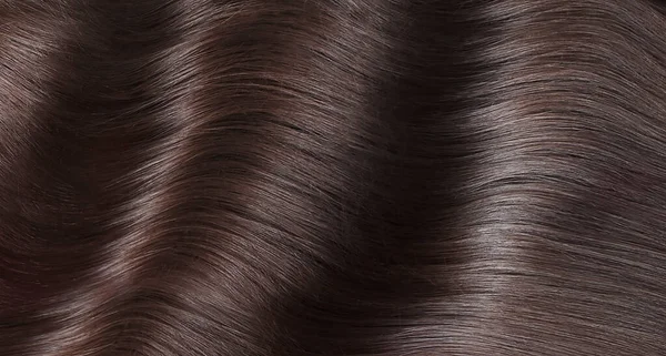 A closeup view of a bunch of shiny straight brown hair in a wavy curved style